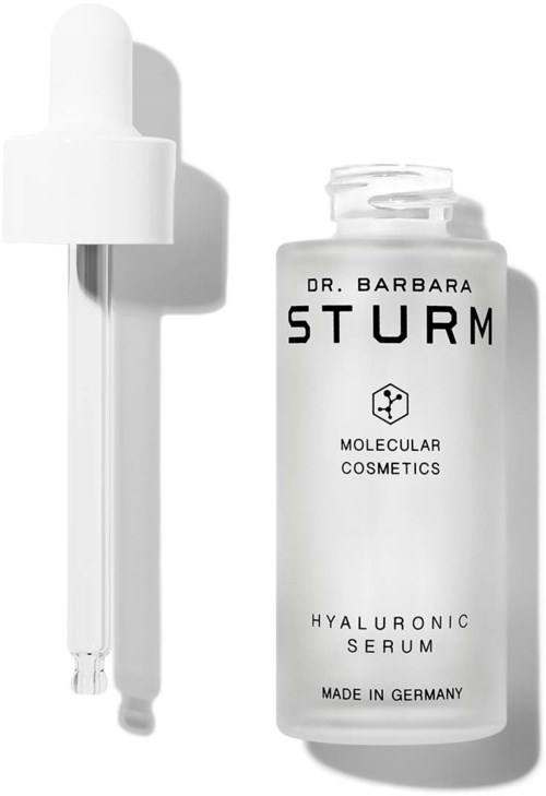 En hvit flaske merket 'Hyaluronic Serum' med en pipette ved siden av, og tekst som indikerer at den er laget av Dr. Barbara Sturm.