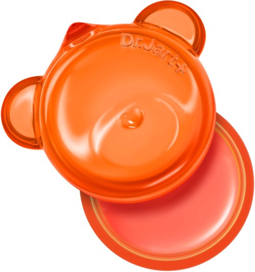 Orange container shaped like a bear's face with a lid and a small hole on top. Contains skincare product.