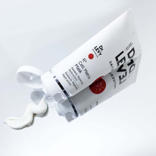 Drares av Dr. Leivy R3 Cell Matrix Mask med kräm som rinner ut på en vit yta.