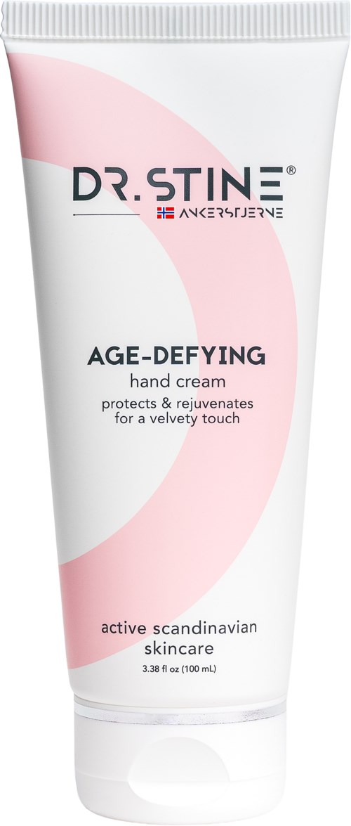Een witte en roze tube handcrème van Dr. Stine, gelabeld voor leeftijdsvermindering en huidbescherming.