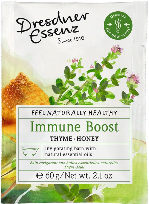 En vit förpackning av Dresden Essence immunförsvarsbad med timjan och honung, med gröna blad, rosa blommor och honungsbit.