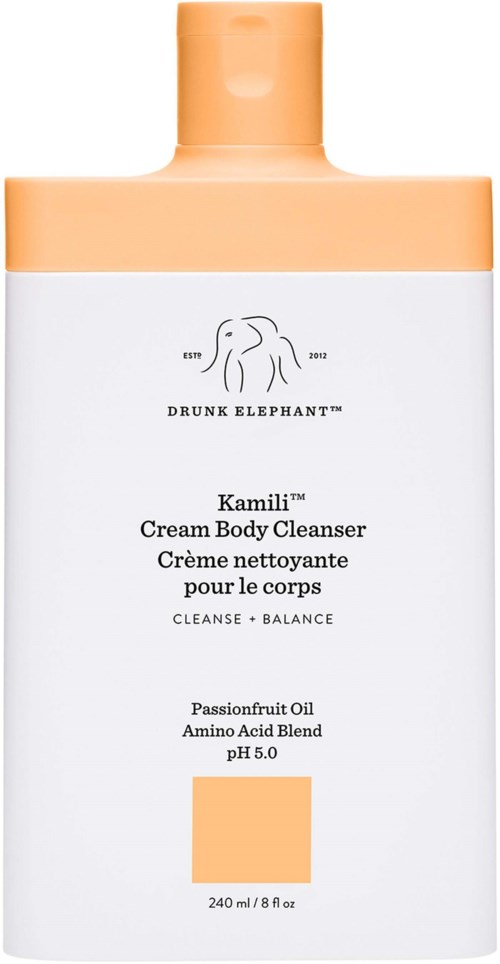 En hvit og ferskenfarget flaske merket 'Drunk Elephant Kamili Cream Body Cleanser' med en elefantlogo.