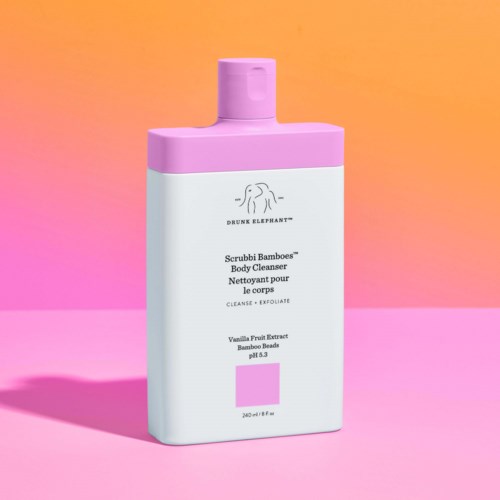 En hvit kroppsvaskeblandingflaske med rosa kork og etikett, med en logo, på rosa og oransje bakgrunn.