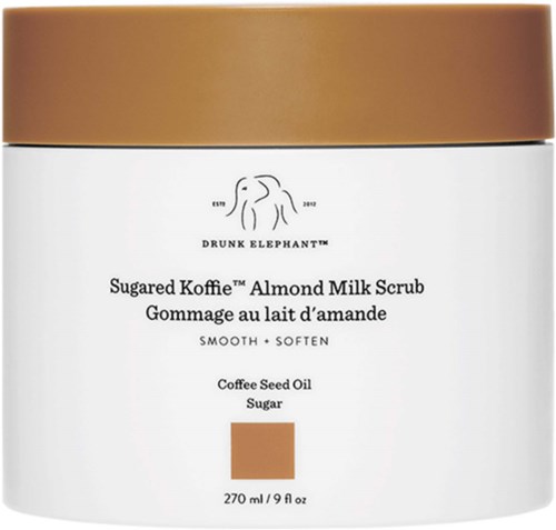 En hvit krukke med gullokhold som inneholder Mandelmelk Skurekrem, med ingredienser som kaffebørolje og sukker, lover glatt hud.