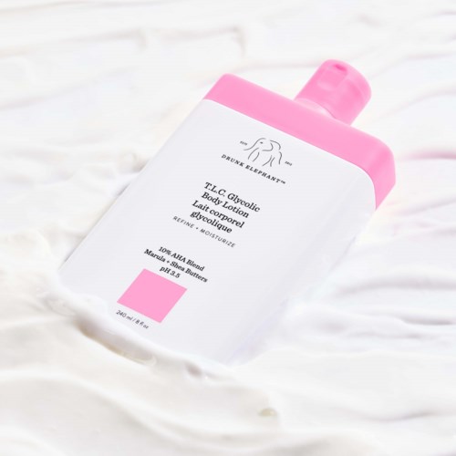 Rosa og hvit bodylotionflaske med rosa kork, plassert på hvit overflate.