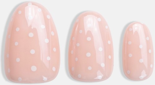 Three pink artificial nails with white polka dots, different sizes aligned from largest to smallest.