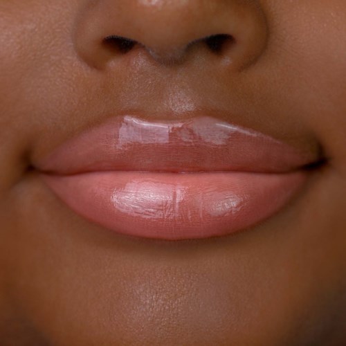Close-up of lips with shiny, light pink lipstick on skin tone. Almost touching the nose.