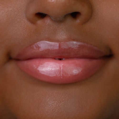 Close-up of lips and nose with shiny, light pink lips and smooth skin.