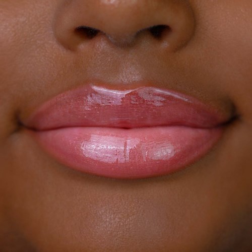 Close-up of lips with glossy pink lipstick on a person's face.
