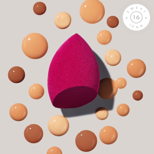 A pink makeup sponge surrounded by various shades of foundation drops on a light background.