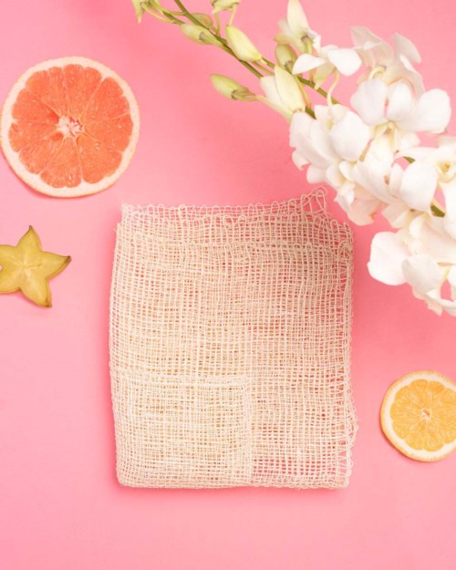 A pink background with white flowers, two citrus slices, a star-shaped fruit, and a beige mesh cloth.
