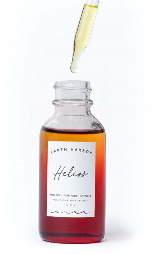 A small brown bottle with a white label, a dropper releasing a yellow liquid, labeled 'Helios' for skin health.