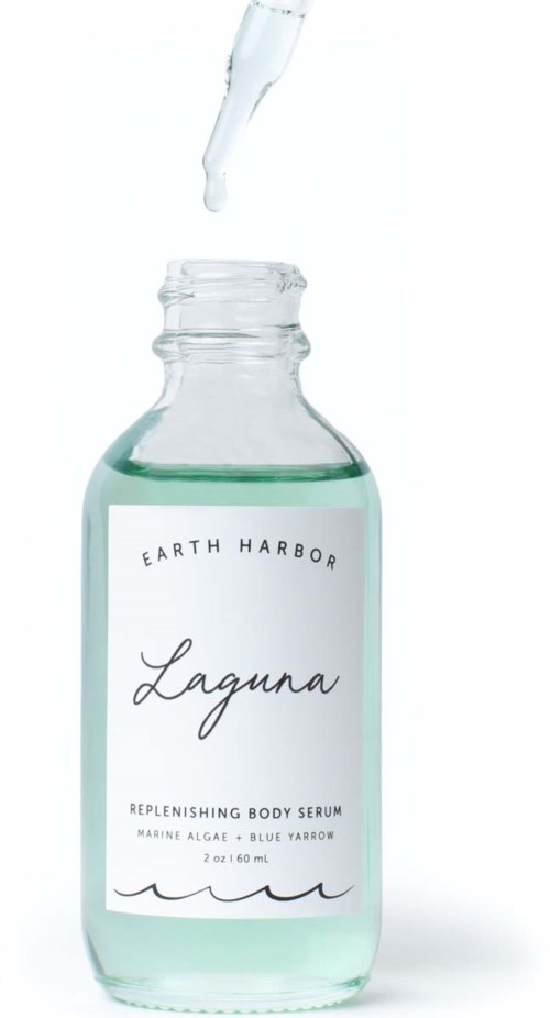 A glass bottle with serum being dropped into it, labeled 'Earth Harbor Laguna' for body care.