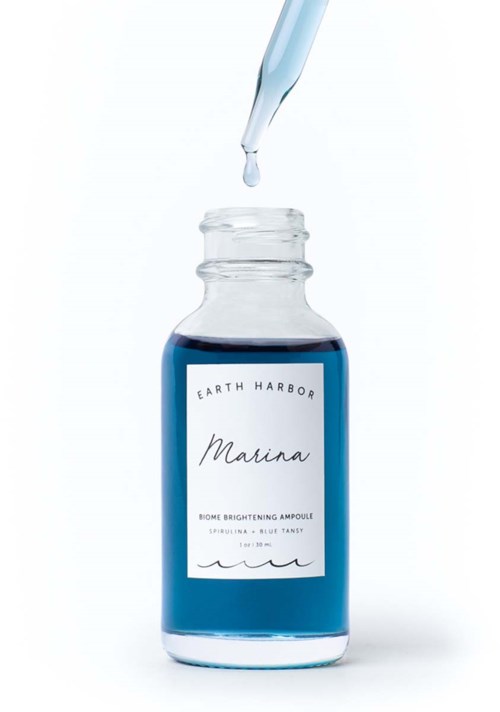 A small glass bottle with blue liquid and a dropper above it. The label reads 'Earth Harbor Marina'.