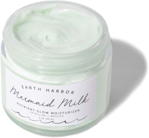 Een pot met groene vochtinbrengende crème met een witte label die zegt 'Earth Harbor Mermaid Milk' en plantaardige ingrediënten bevat.