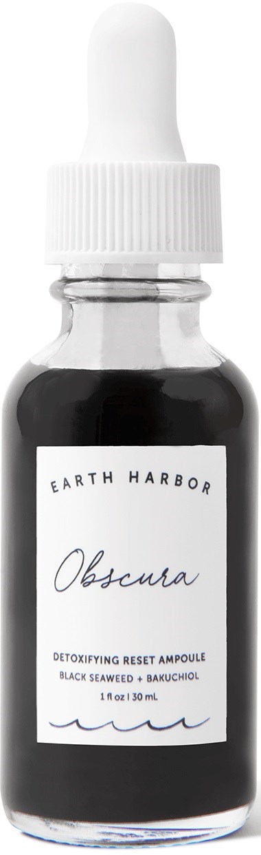 A small glass bottle with a white dropper cap, labeled Earth Harbor Obscura, contains dark liquid cream or serum.