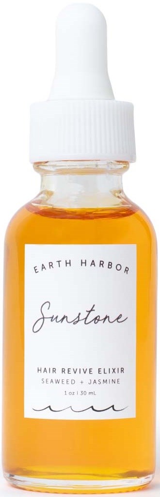 A small glass bottle with orange liquid and a white dropper cap, labeled Earth Harbor Sunstone hair elixir.
