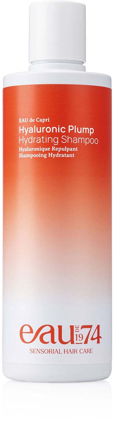 A tall white bottle with a red-orange label, labeled 'Hyaluronic Plump Hydrating Shampoo,' from Eau 74.