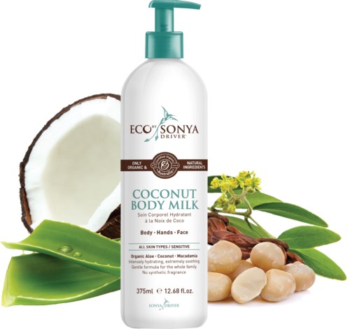 A white bottle of coconut body milk with green pump, surrounded by coconut, aloe vera, and macadamia nuts.