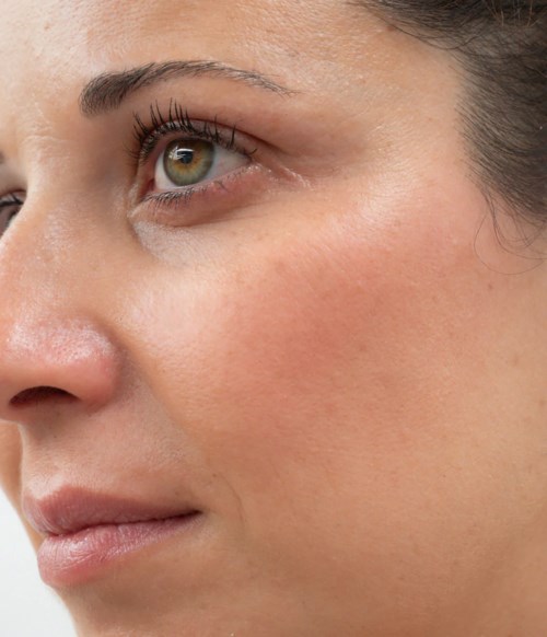 Close-up van het gezicht van een vrouw met oog, wang en deel van neus, heldere huid en make-up.