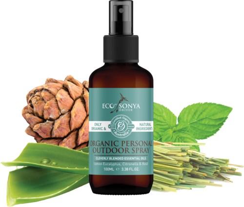 Bruine spuitfles met label 'Organic Personal Outdoor Spray' omringd door dennenappel, muntbladeren en aloë vera.