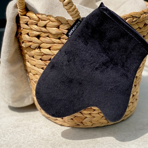 A black Christmas stocking hangs on a woven basket filled with blankets.