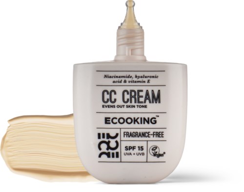 A white bottle of face cream with a nozzle, labeled with ingredients and SPF 15, next to a stack of cream.