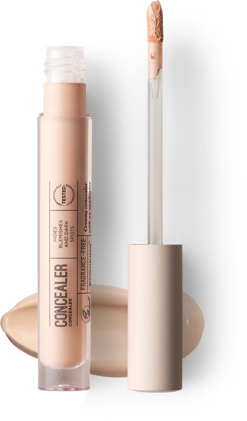 Concealer tube with applicator, beige liquid spilled next to it, on a white background.