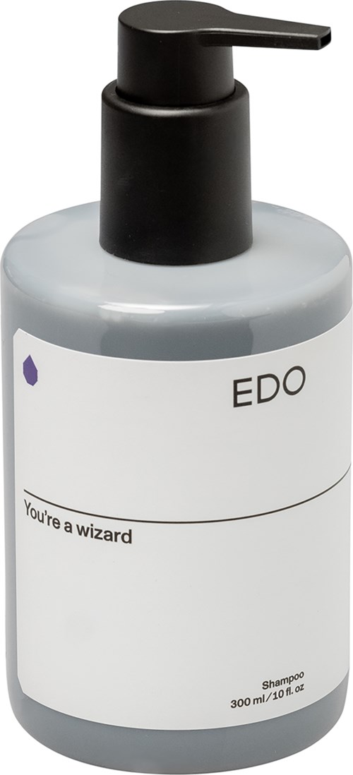 Eine graue Shampooflasche mit schwarzem Pumpkopf und einem einfachen weißen Etikett mit der Aufschrift 'EDO' und 'You're a wizard.'