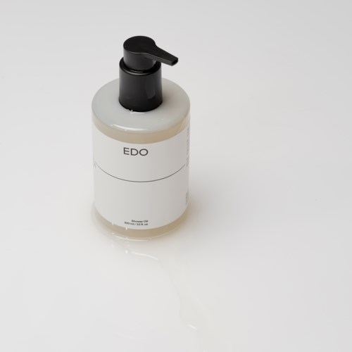 Eine weiße Flasche mit schwarzen Pumpen, beschriftet "EDO", steht auf einer weißen Oberfläche.