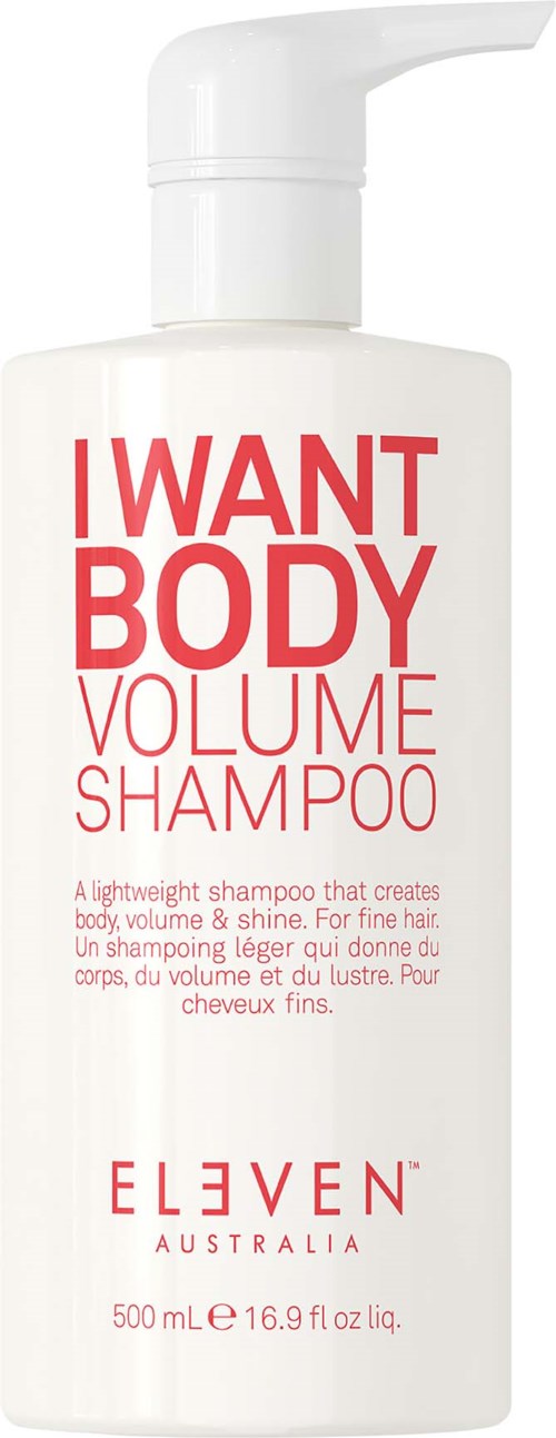 En vit flaska med I WANT BODY volymschampo med pump och röd och rosa text.