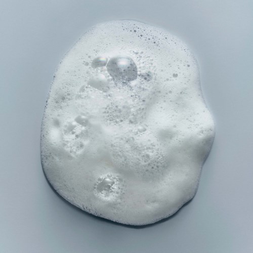 A foamy, bubbly substance, possibly soap or detergent, on a flat surface.