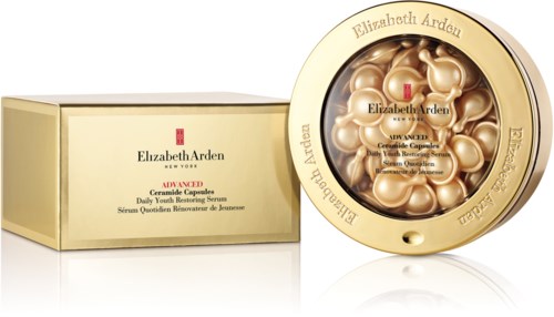 Round container with gold capsules inside and a box beside it, both branded Elizabeth Arden, containing skincare capsules.