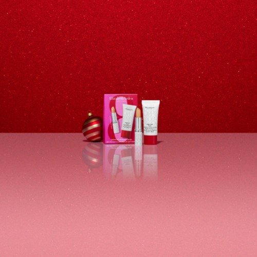Beauty gift set with skincare and makeup products, pink packaging, and a Christmas ornament on a pink surface.