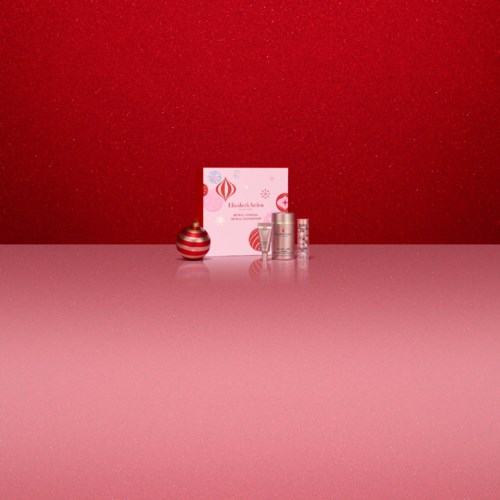 Cosmetic products, a box with a logo, and a small striped Christmas ornament on a pink and red background.