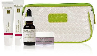 A skincare set including two tubes, one bottle with dropper, one small jar, and a green and white bag.