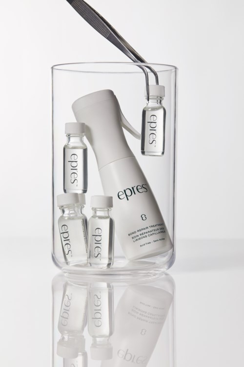 A skincare set in a glass includes small bottles, a larger bottle, a tube, and tweezers, all with "epres" branding.