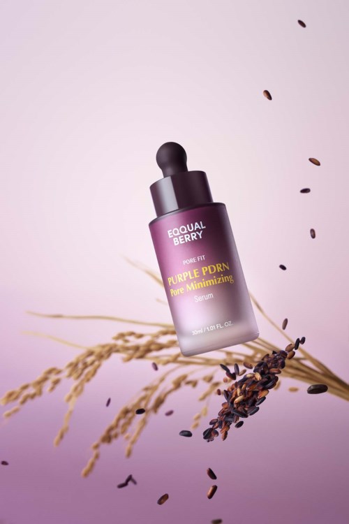Een paarse huidverzorgingsfles met label 'Equal Berry Purple PDRN' en planten en zaden eromheen.
