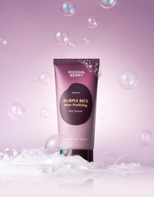 Een tube met Purple Rice Pore Purifying Pack Cleanser omgeven door bellen tegen een roze achtergrond.