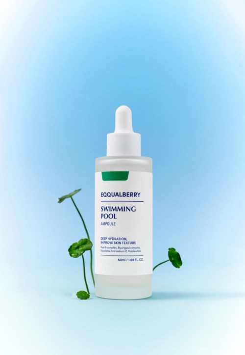 Kleine fles met het label 'Swiming Pool' met groene label, omgeven door kleine groene plantblaadjes.