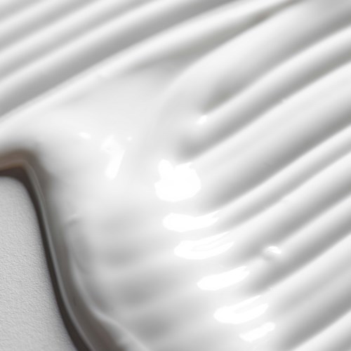 A close-up of a white, creamy substance spread in smooth lines on a surface.