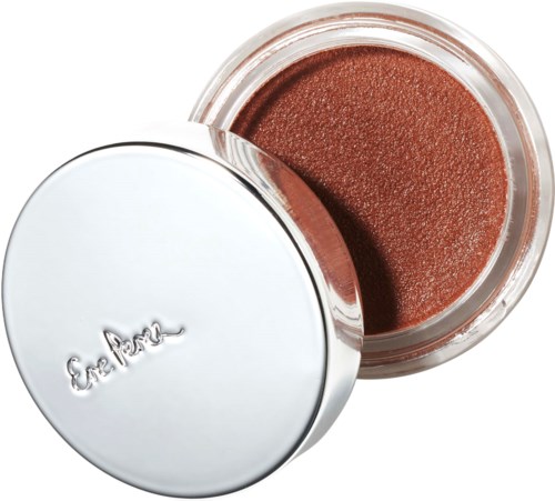 A small open container with brownish-orange makeup or eyeshadow inside. Silver lid with some writing.