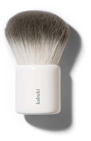 Een witte handgreep met de merknaam 'kabuki' en een grote, pluizige, grijs-witte make-upkwast erboven.