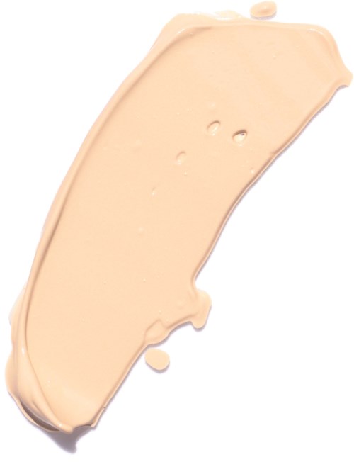 En prov av beige foundation eller concealer med tre små hål och en droppe på vit bakgrund.