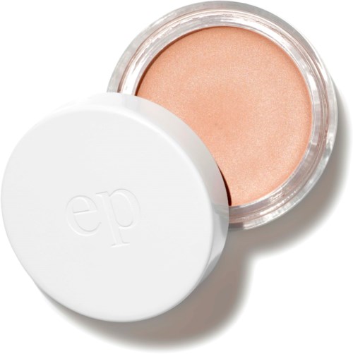 Een kleine ronde container met een perzikkleurig make-up product en een witte deksel met 'ep'.