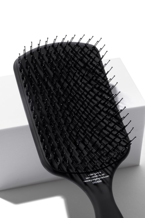 Eine schwarze Haarbürste mit breiten Zinken, auf einer weißen Oberfläche.