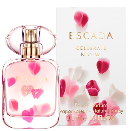 Een parfumfles met het label Escada, omringd door roze en witte bloembladeren op en rond de fles en de doos.