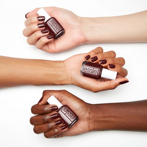 Three hands with dark, medium, and light skin tones hold Essie nail polish bottles with matching nail colors.