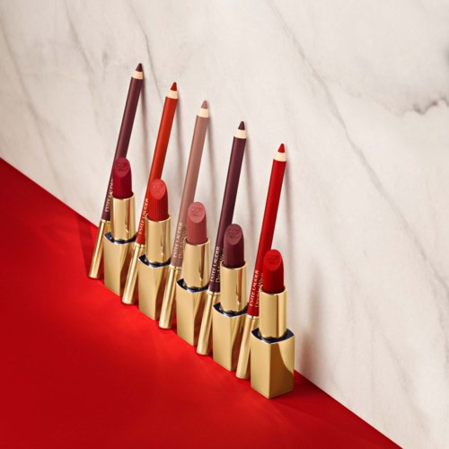 Lipsticks in verschillende tinten liggen naast een witte marmeren achtergrond en een rode ondergrond.