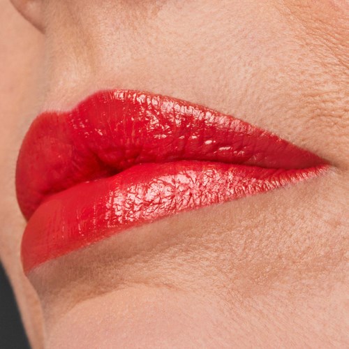 Nahaufnahme von Lippen mit rotem Lippenstift, leicht geöffnet, zeigt glatte Haut.